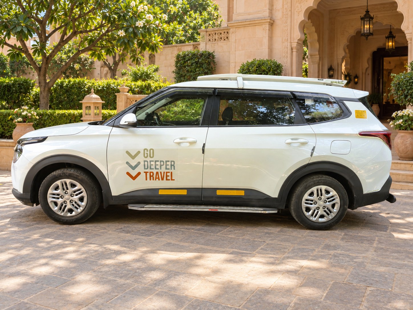 The Go Deeper Travel Kia Carens parked outside a heritage hotel entrance